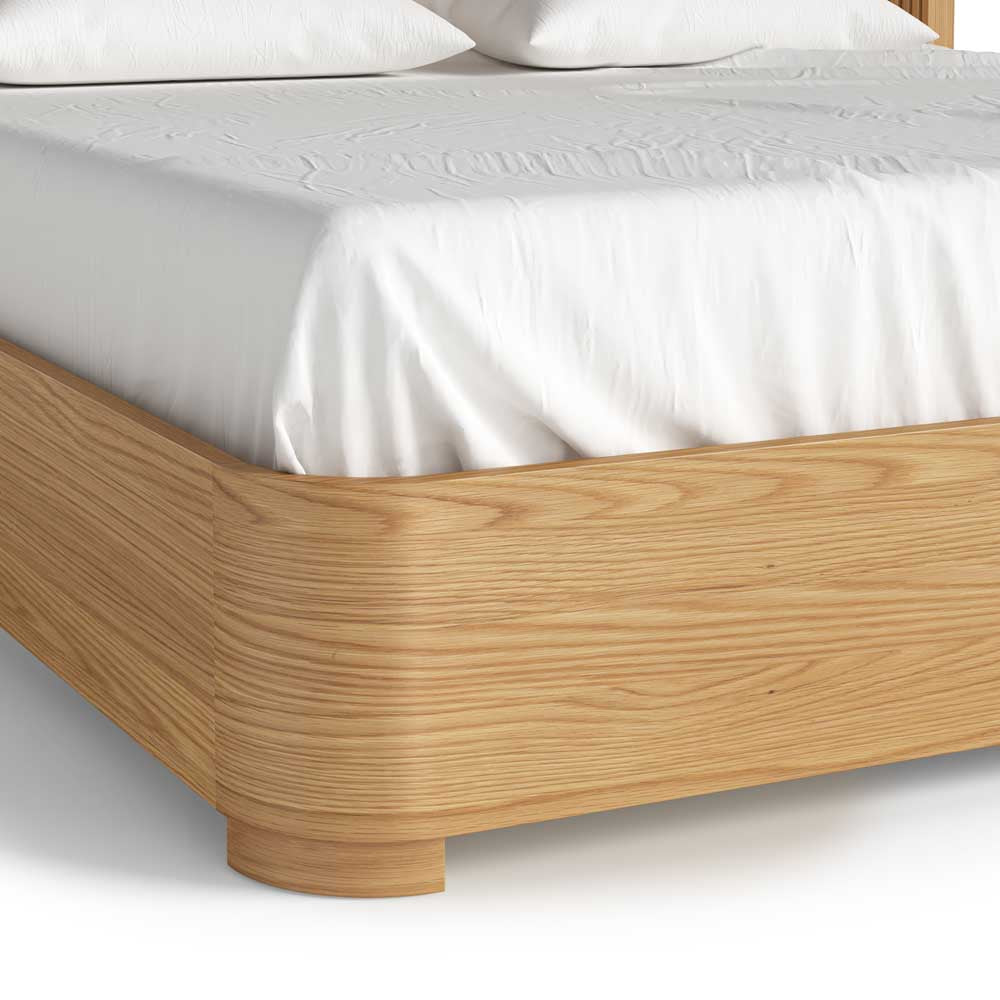 Wooden bed frame with white bedding on a plain background