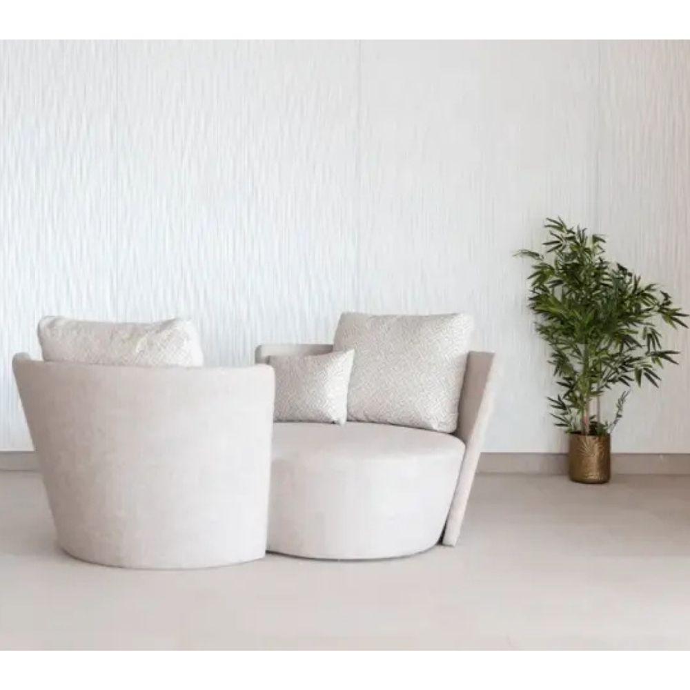 Modern beige infinity sofa with decorative pillows in a minimalistic room with a plant.