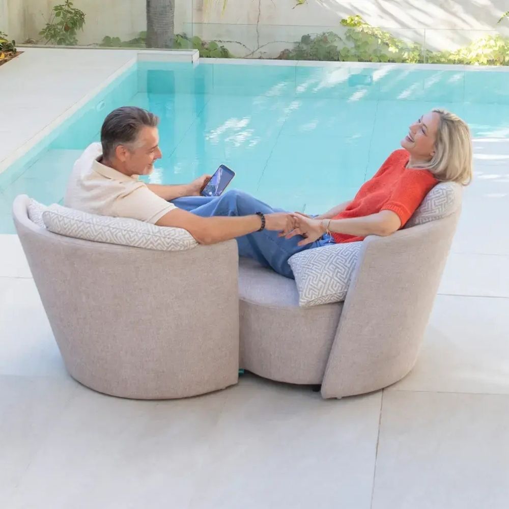 Two people sitting on a modern infinity sofa by a pool