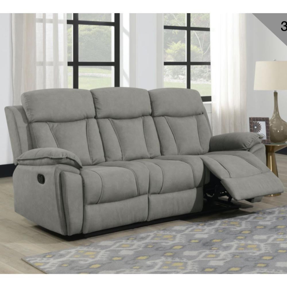 Gray reclining sofa in a living room setting with large windows and a lamp.