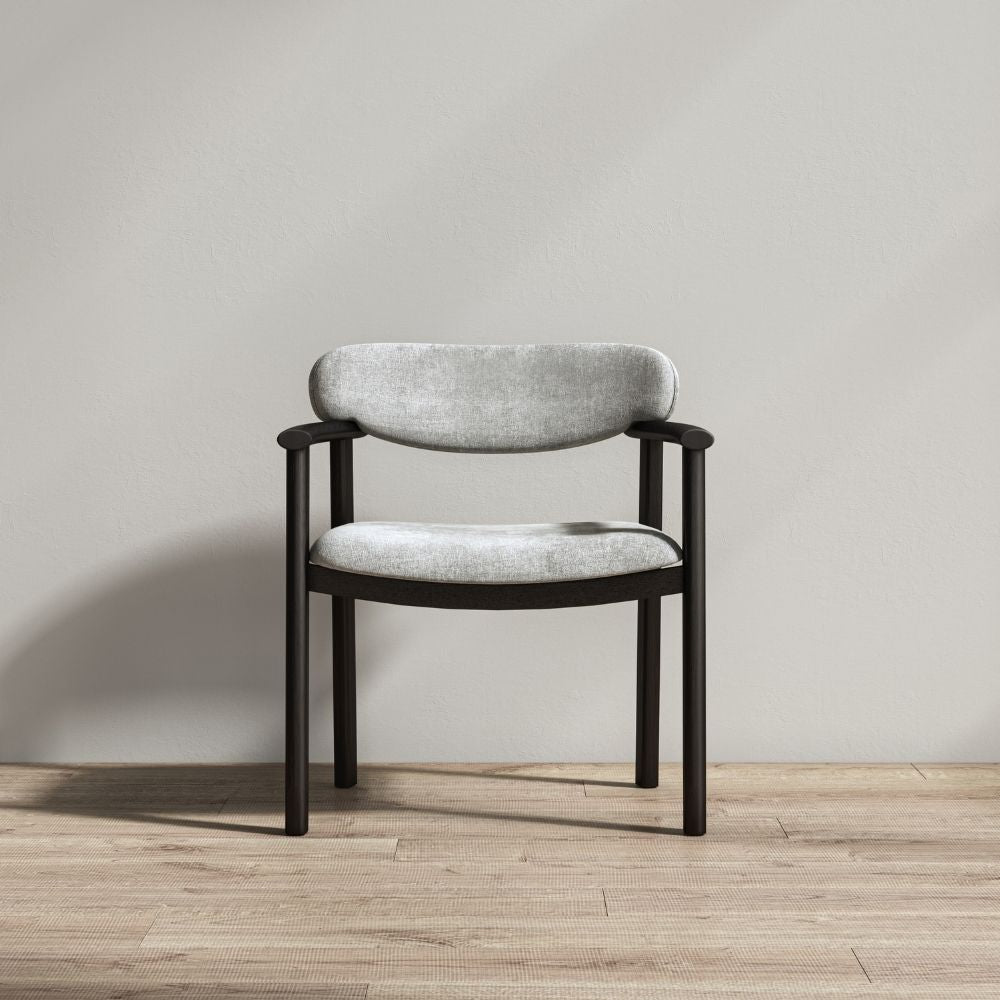 A modern dining chair with a light gray textured fabric seat and backrest, supported by a curved dark wood frame, set against a neutral gray wall and light wood floor.