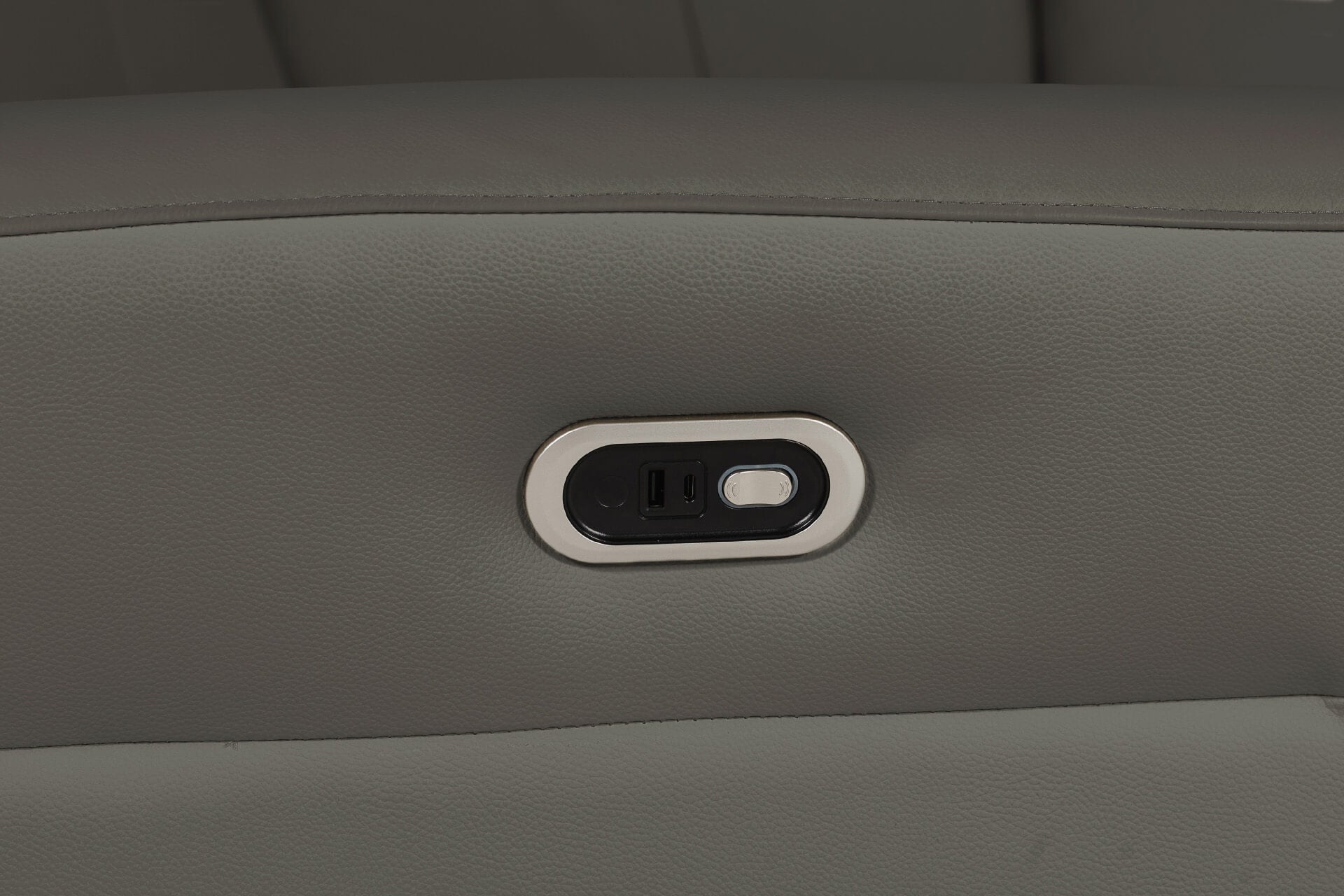 Close-up of charging port on grey leather electric reclining chair.