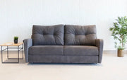 Gray sofa in a room with a white wall and a small table.
