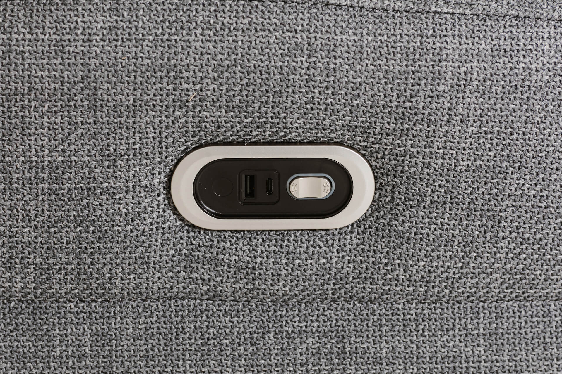 Close-up of a textured gray fabric chair arm with inbuiltcharging ports