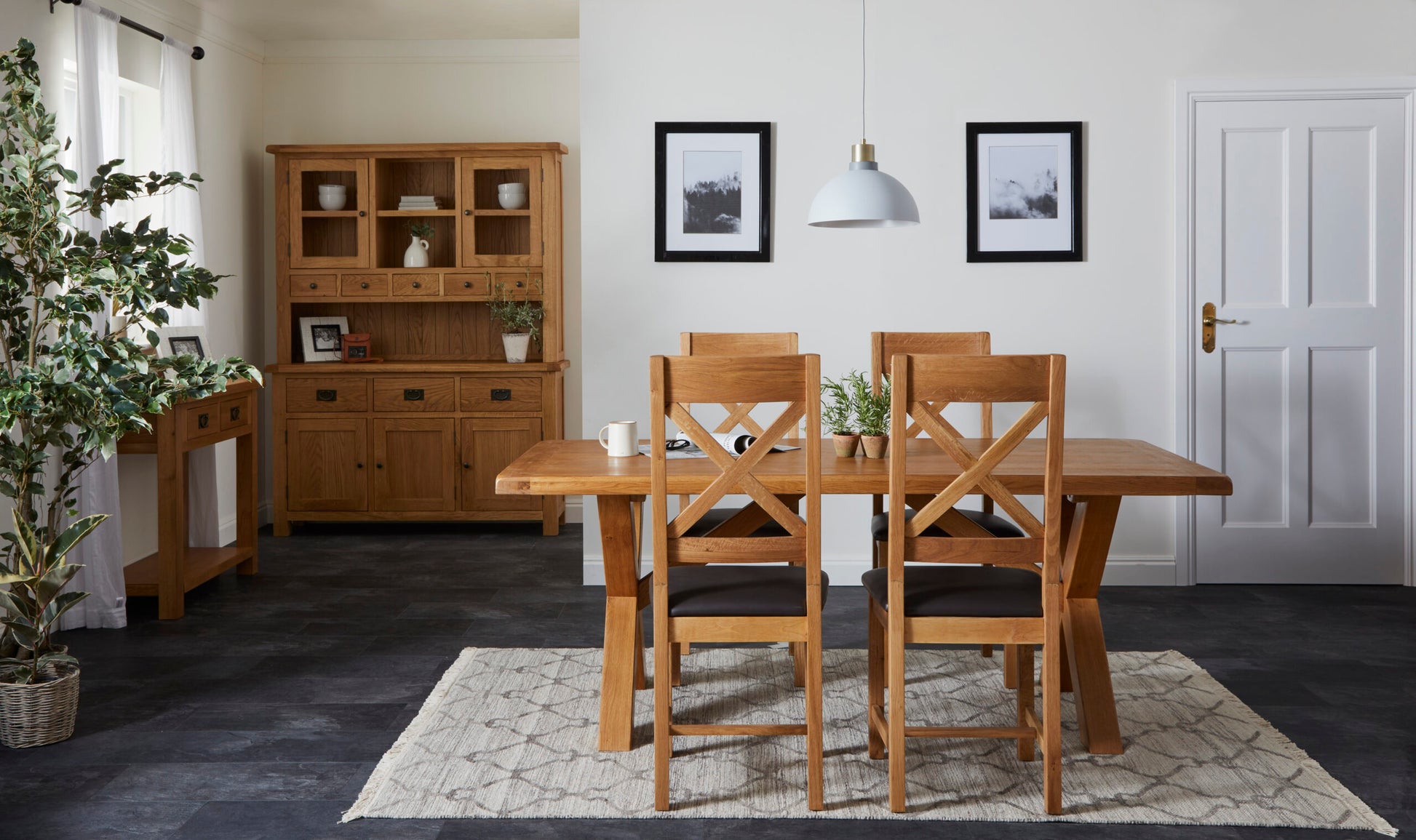 lifestyle image of 4 oak cross back chairs placed around a table in a homely kitchen.