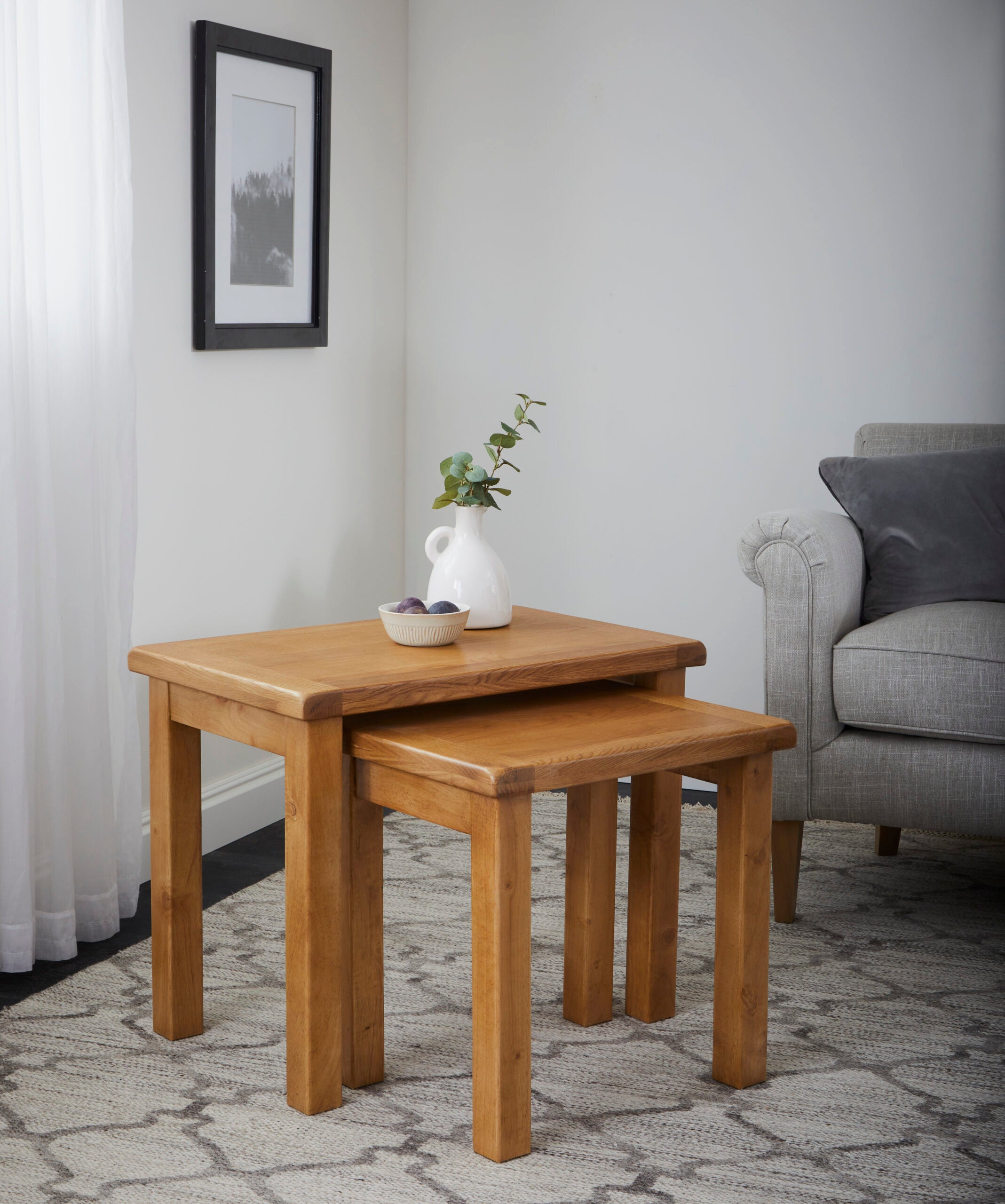 two of a nest of three oak tables with a vase and decorative bowl on top