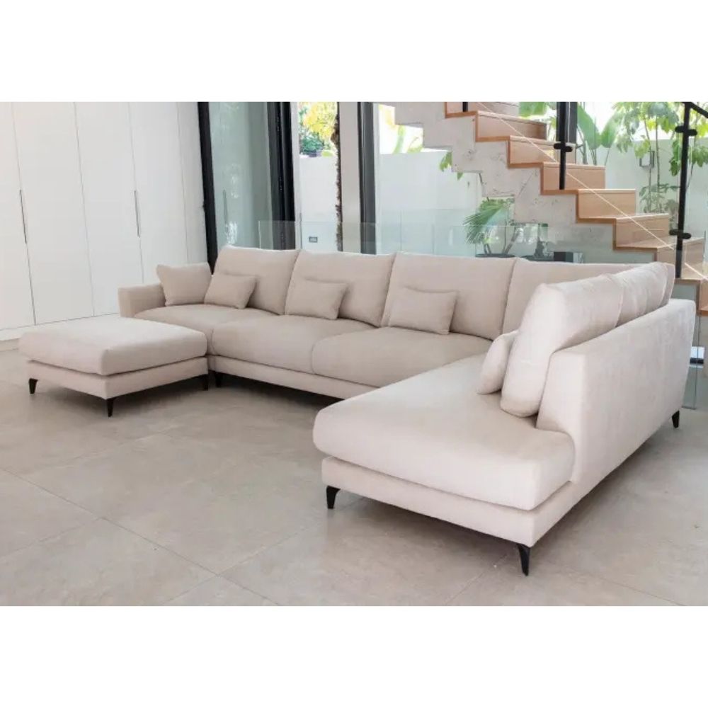 Beige Fama sectional sofa in a modern living room with large windows.