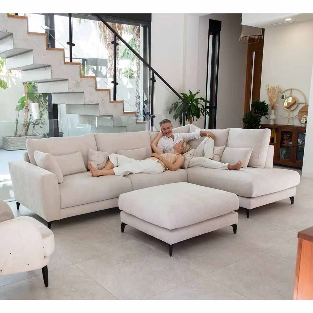 Two people lying on a beige Fama sectional sofa in a modern living room.