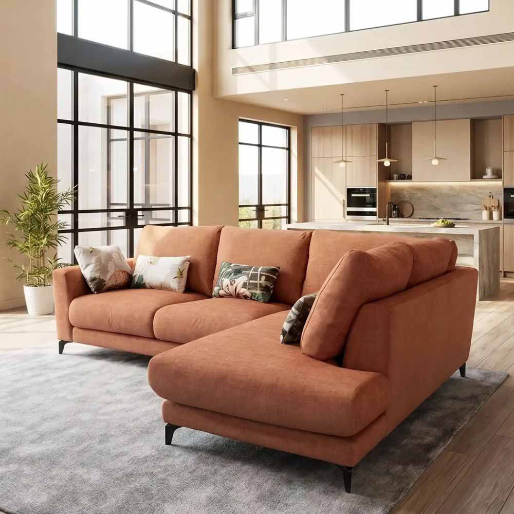 Orange Fama sectional sofa in a modern living room with large windows and kitchen in the background.