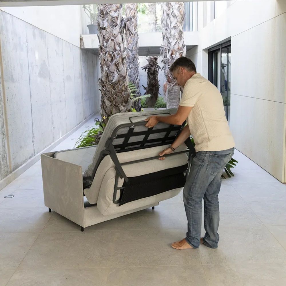 Man converting a sofa bed into a regular sofa in a modern indoor setting.