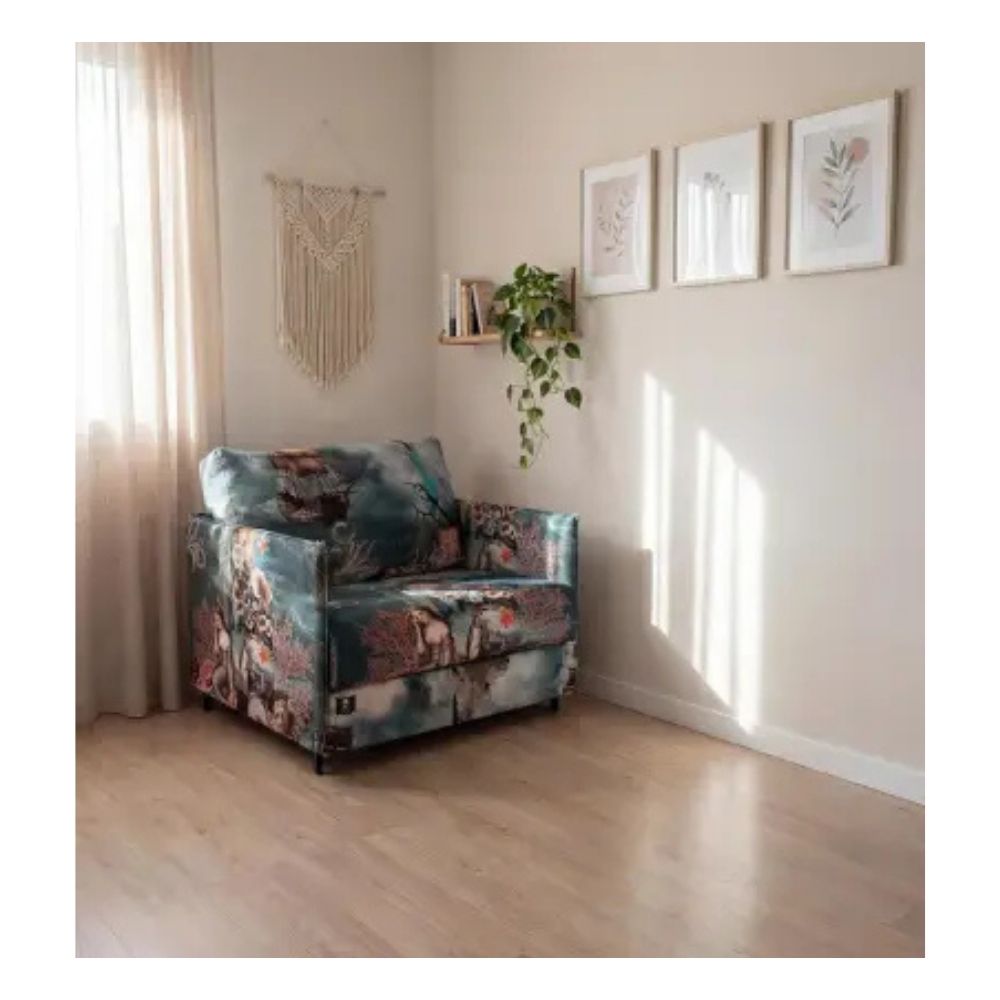 Floral armchair which converts into a sofa bed in a room with light wood flooring and framed pictures on the wall.