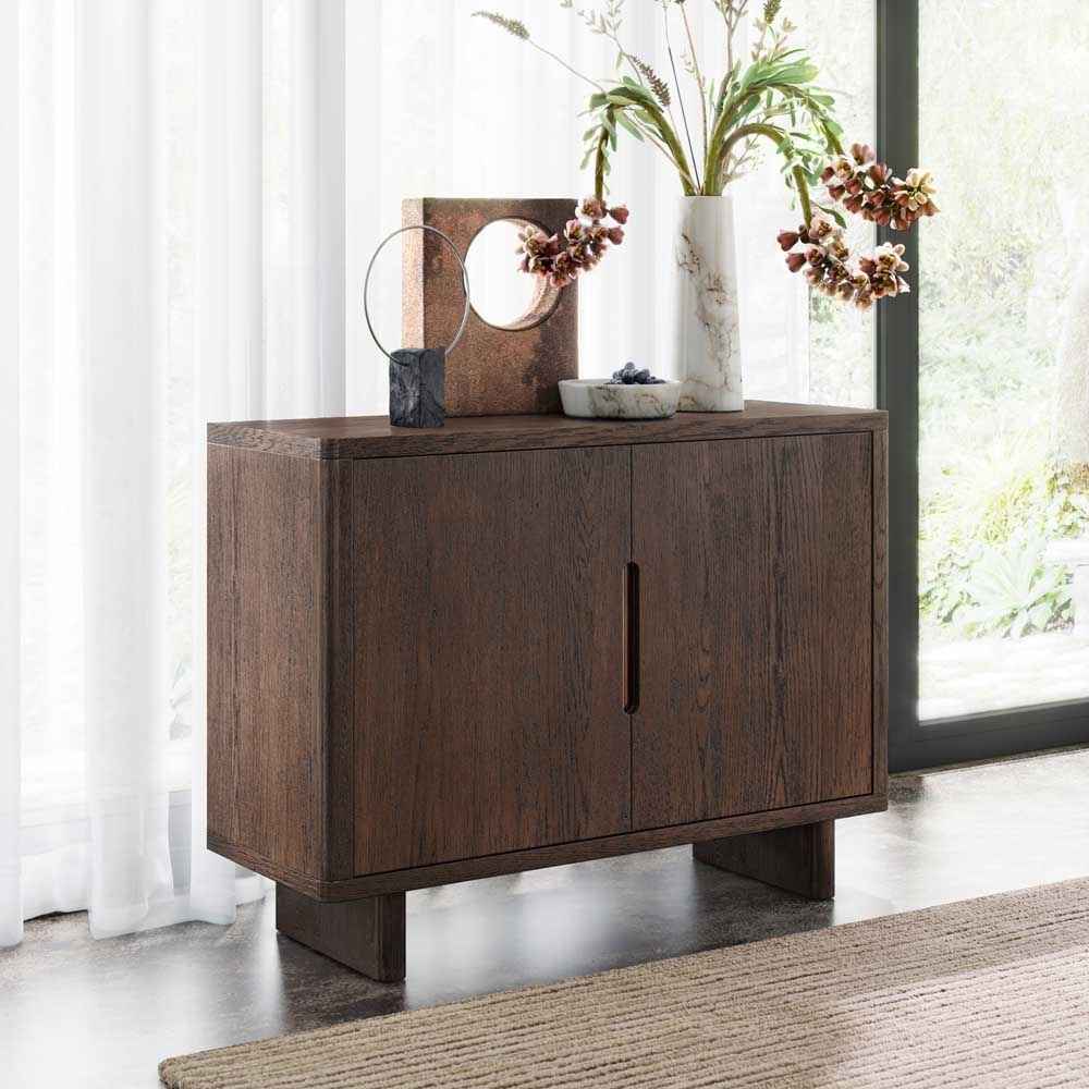 Wooden sideboard with decorative items in a room with large windows.
