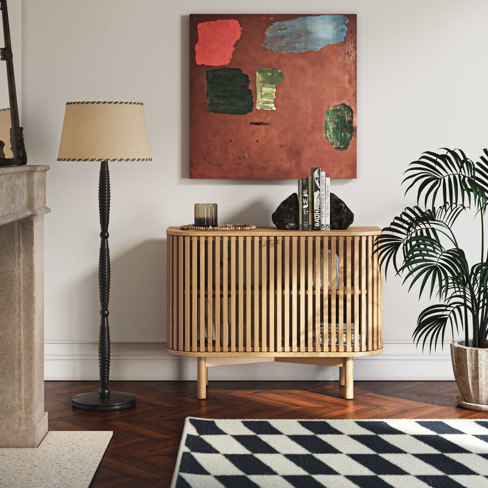 Small sideboard in living room setting, with items within and candles, books and ornaments on top.