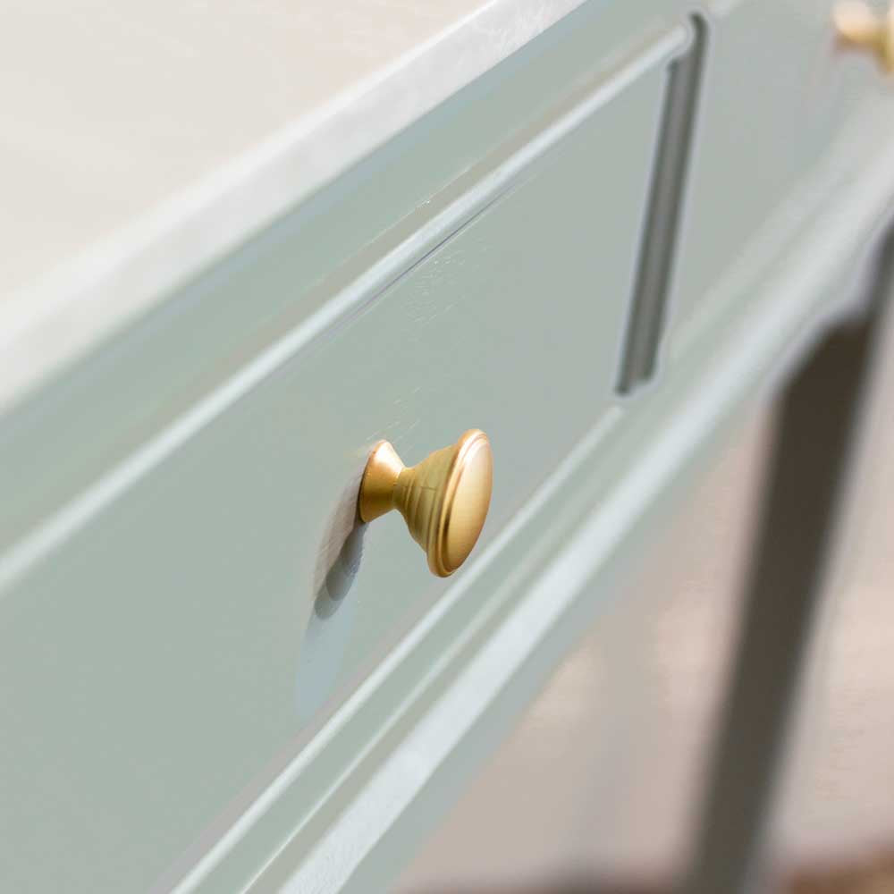 Close up of brushed brass / gold coloured handle on sage green console table drawer