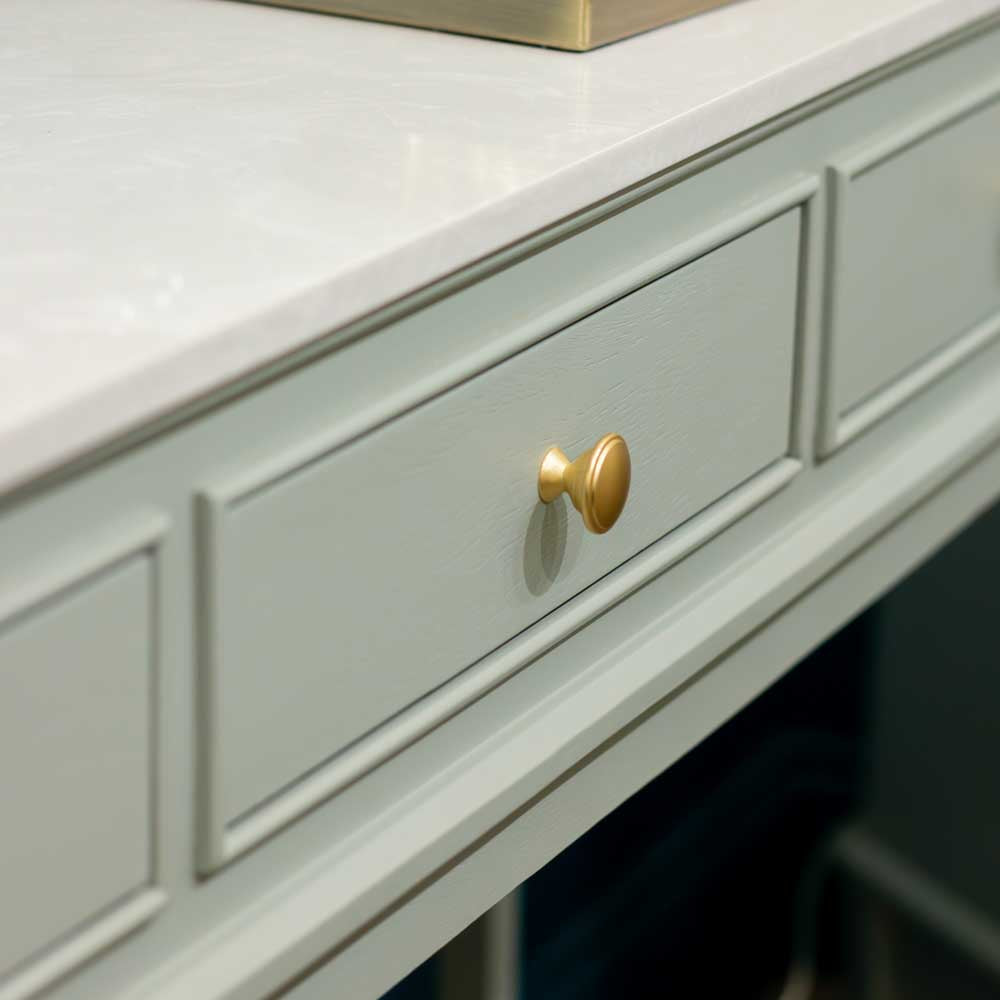 Close up of brushed brass / gold coloured handle on sage green console table drawer, with white marble top