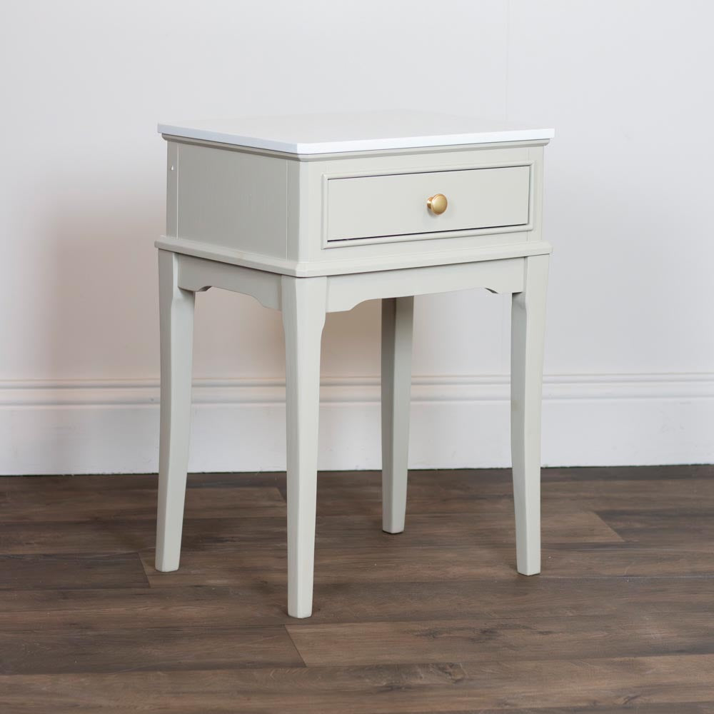 Taupe / beige lamp / accent table with a drawer on a wooden floor against a white wall