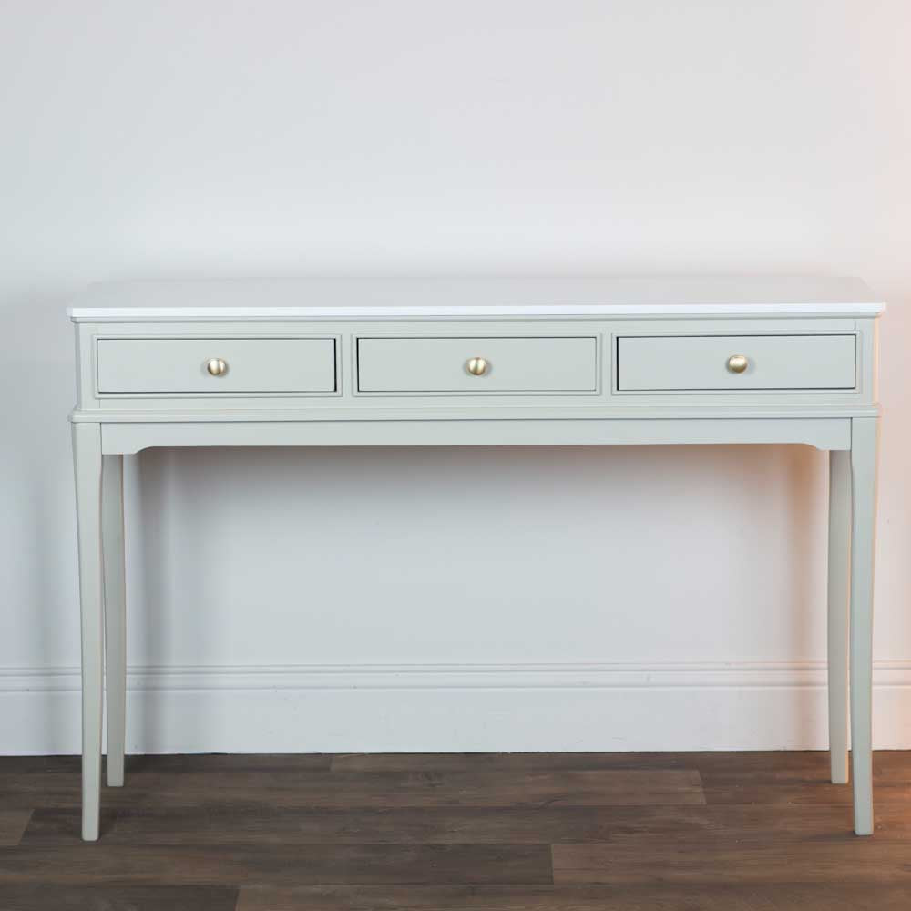 Light beige / stone coloured console table with three drawers and marble top against a white wall.
