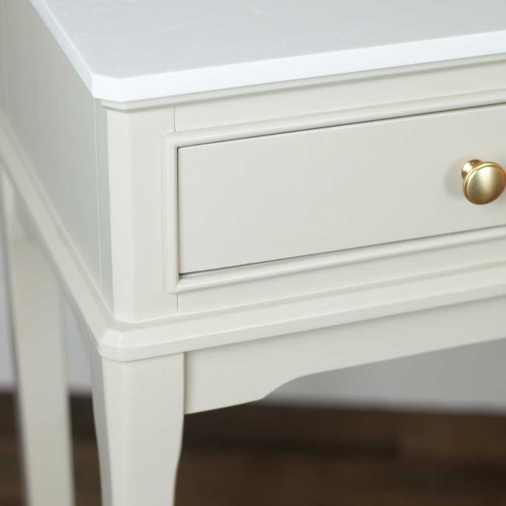 Close-up of a beige / stone coloured wooden console table with a single drawer in view featuring a round gold knob, set against a neutral background.