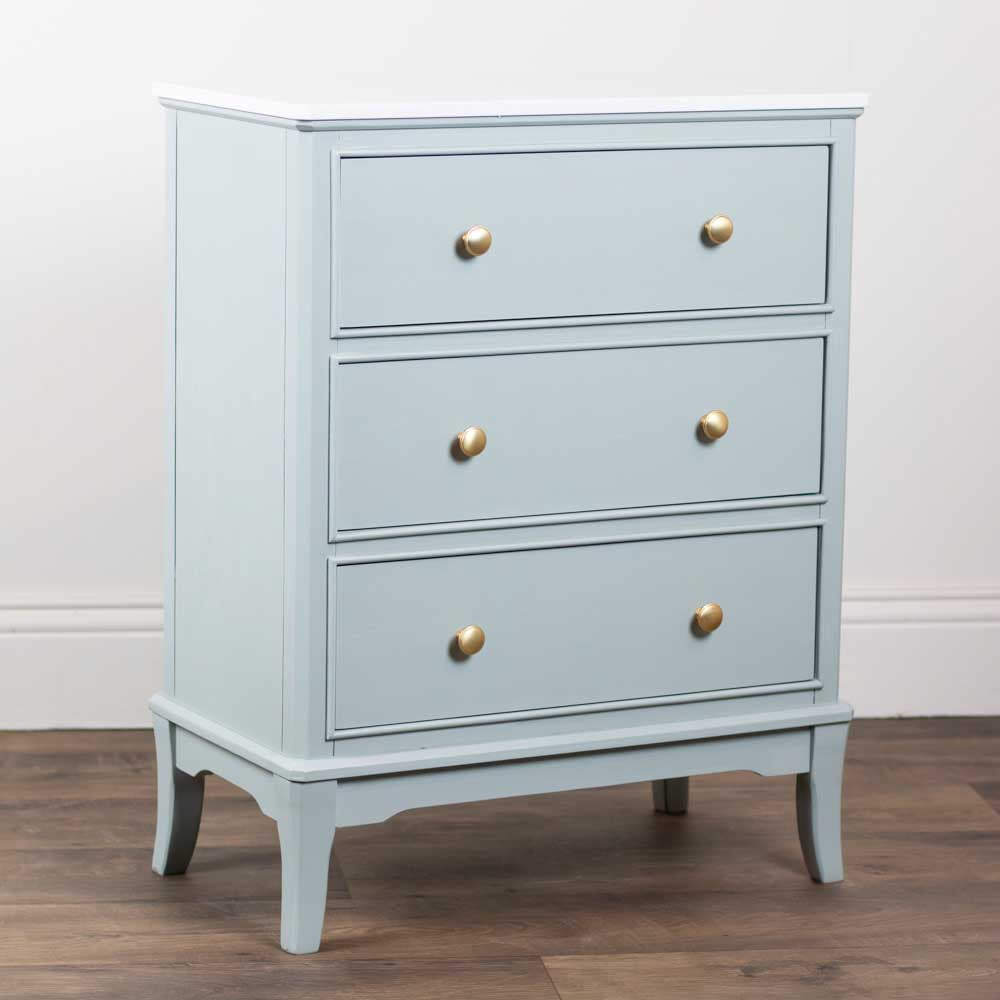 Sage green dresser with gold knobs on a wooden floor and white wall background