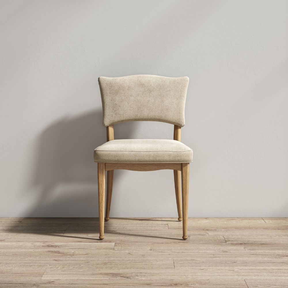 A single upholstered dining chair with a light beige fabric seat and backrest, supported by a natural wood frame with four tapered legs, set against a neutral gray wall and light wood floor.