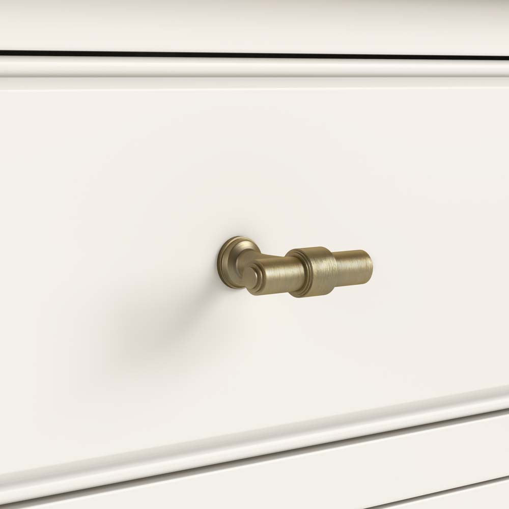 Close-up of a white drawer with a gold T-bar handle