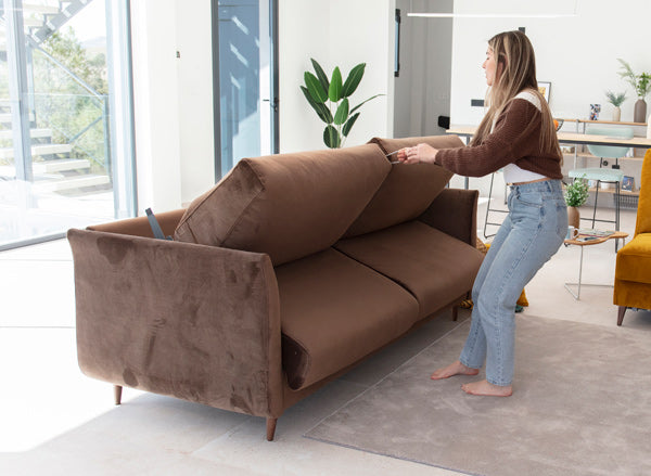 Helsinki Sofa Bed by Fama being easily reclined into its bed form by a user