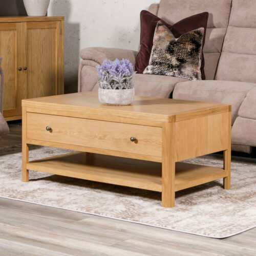 oak rectangle coffee table with storage drawer. Set in a living room with purple plant on top.